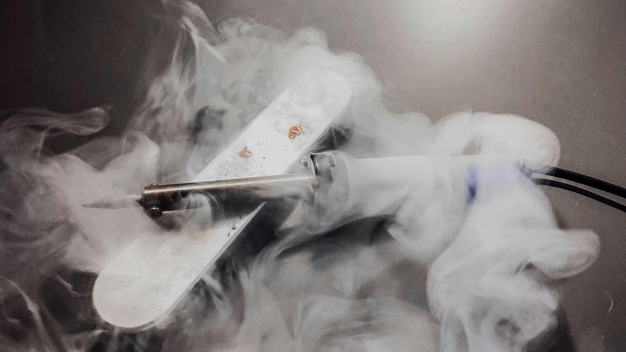 Detailed image of a soldering iron emitting smoke, showcasing its heated tip and white fumes.